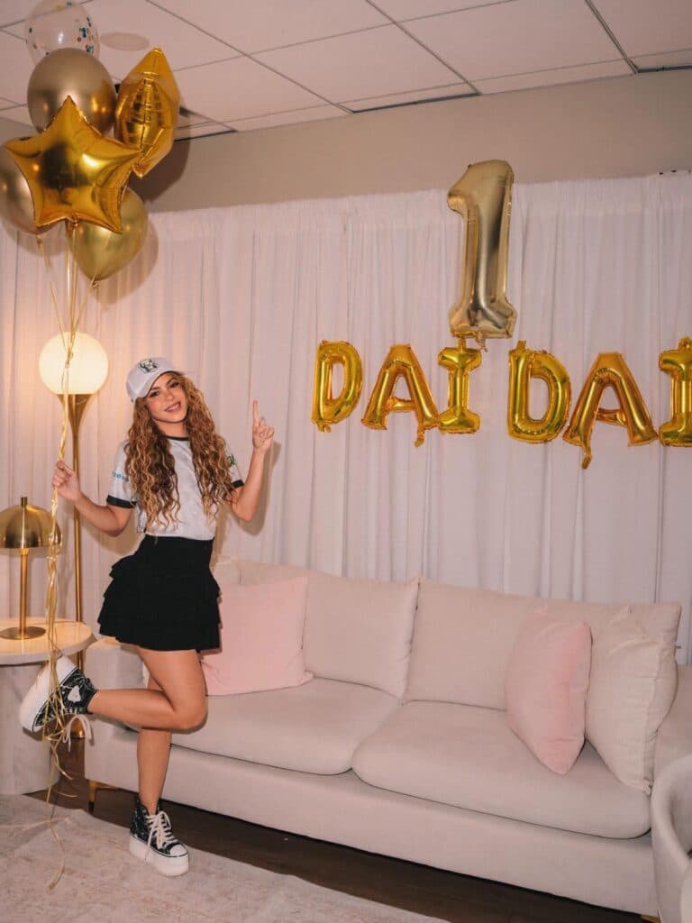Shakira celebra el éxito de "Dai Dai" con globos dorados y una decoración festiva en un ambiente acogedor.
