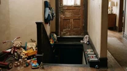Escalera de una guardería con juguetes esparcidos y un sótano oscuro, donde se hallaron 12 niños hacinados en un automóvil.