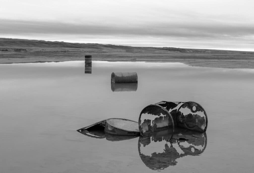 Barriles oxidados en un cuerpo de agua, reflejando preocupaciones sobre residuos radiactivos en el océano Atlántico.
