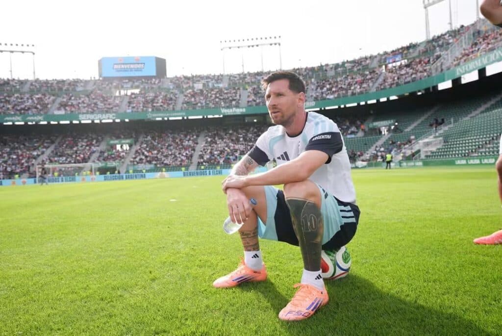 Lionel Messi sentado en el campo de juego, con la camiseta de la Selección Argentina, reflexionando sobre su retiro del fútbol internacional.